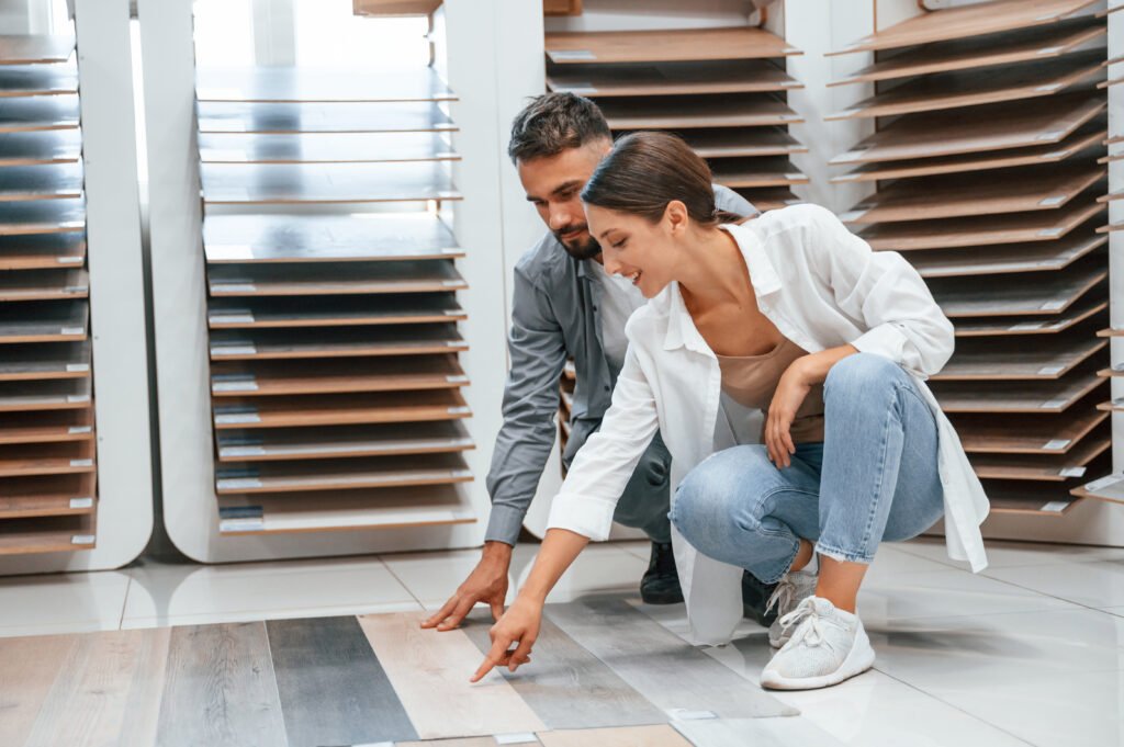 Sitting and choosing parquet. Woman and man is in the store of goods for the home - Luxury Finish Flooring